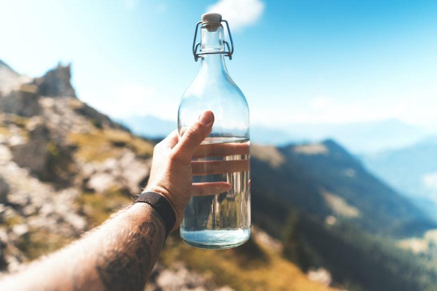 hand holding glass water bottle